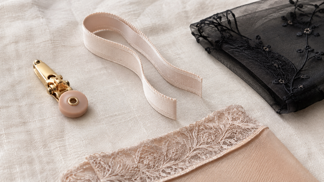 Garter belt hardware and fabric: a suspender clip, satin elastic strap, embroidered mesh and a stocking welt