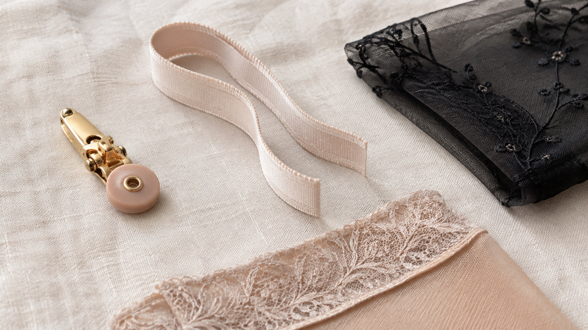 Garter belt hardware and fabric: a suspender clip, satin elastic strap, embroidered mesh and a stocking welt