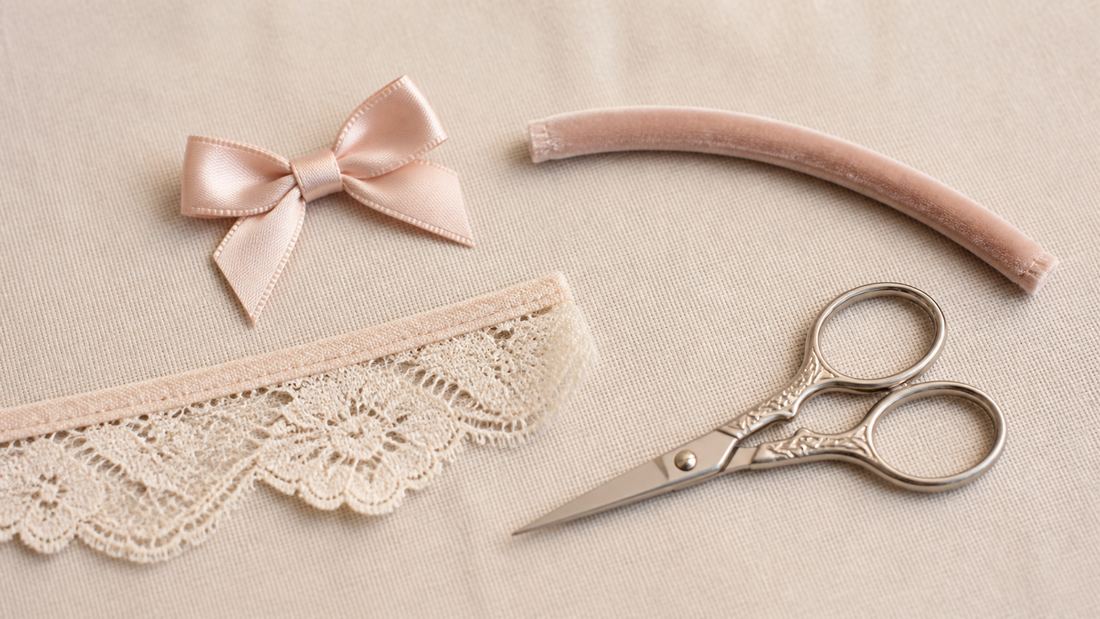 Macro still life of a satin bow, a length of velvet-covered boning, a bound lace edge and fine embroidery scissors on linen