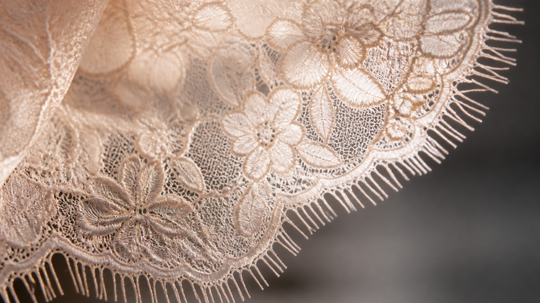 Macro of French Chantilly-style lace with raised floral pattern and eyelash scalloped edge
