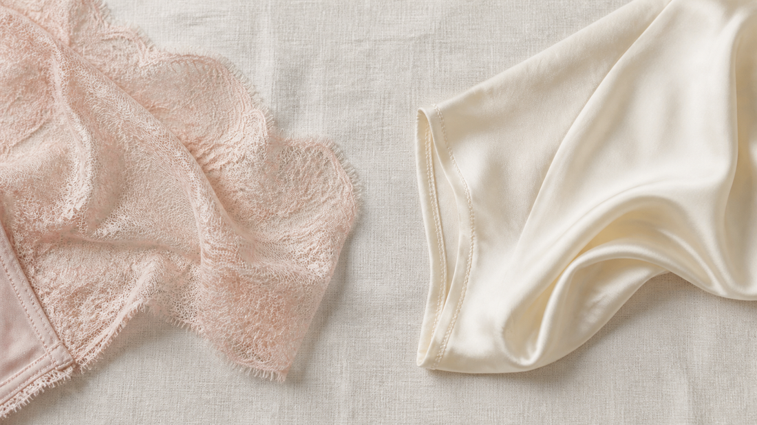 Flat lay on cream linen of a blush French lace lingerie panel beside a smooth ivory silk panel, showing the difference in weight and opacity