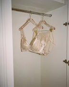 Darette Bare Minimum Silk Set in Champagne - the silk and lace bra and brief hanging in a closet