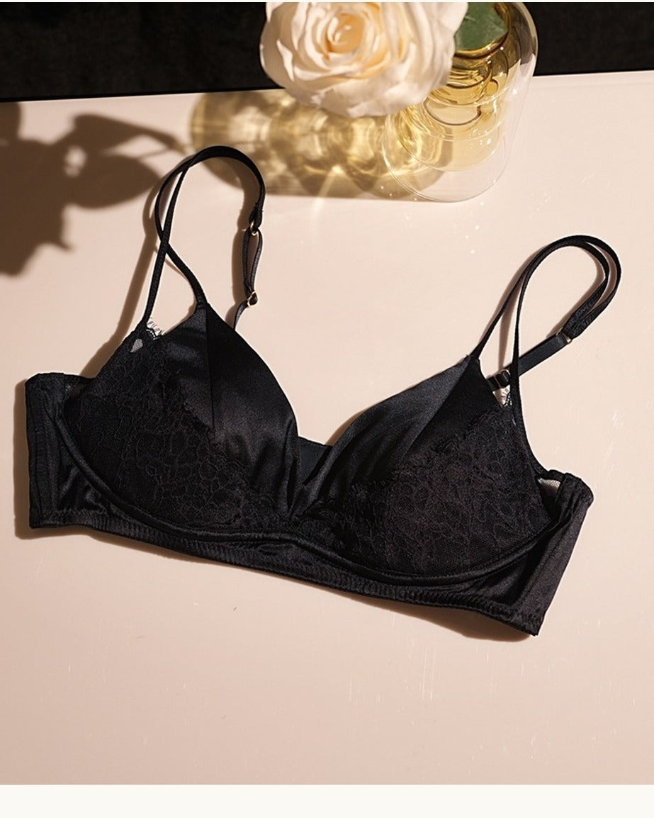 Darette Bare Minimum Silk Set in Noir - flat lay of the silk and lace bra against a floral backdrop