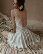 Back view of the Darette Cool It Slip in Crème - open-back strap detail shown on rumpled bedding