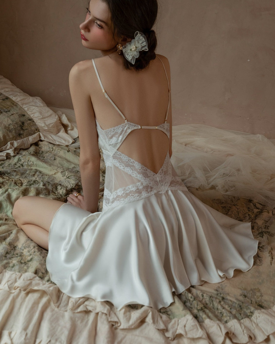 Back view of the Darette Cool It Slip in Crème - open-back strap detail shown on rumpled bedding