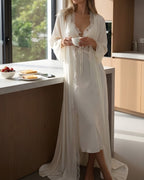 Darette Court of One Set in Ivory - satin gown and robe, standing at a kitchen counter with coffee