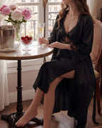 Darette Cover Story Set in Noir - lace robe and gown, seated at a table set with flowers and champagne