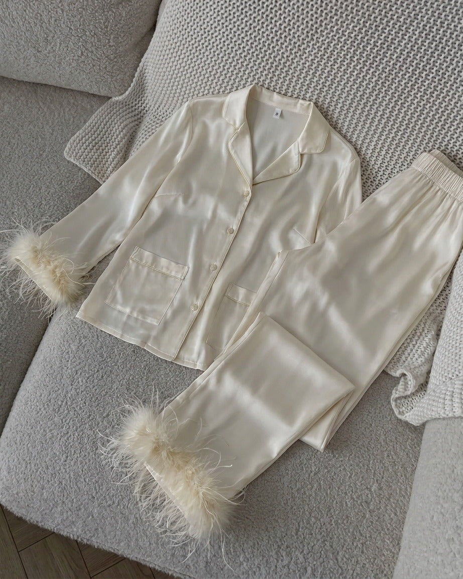 Darette Feather Weight Silk Set in Ivory - satin pajama set with feather cuffs, laid flat on a knit throw