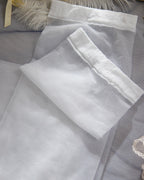 Flat lay of the Darette Fine Print Garter Set in Ivory - folded lace and satin fabric pieces