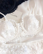 Darette Half Truth Half-Cup Set in Ivory laid flat, showing the floral lace bra and matching scalloped briefs