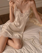 Darette Lash Line Lace Slip in Champagne - front view seated on the bed with a pearl necklace on the sheets