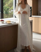 Darette Late Start Robe in Ivory - long lace-trimmed satin robe, standing at a kitchen counter with tea and toast