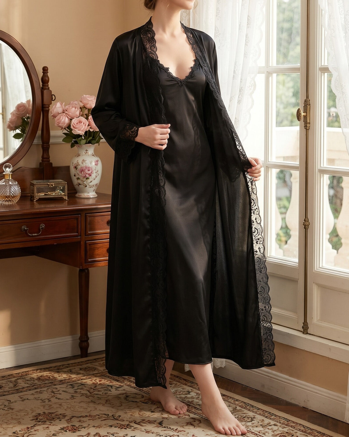 Darette Late Start Robe in Noir - long satin robe with lace trim, standing beside a vanity mirror