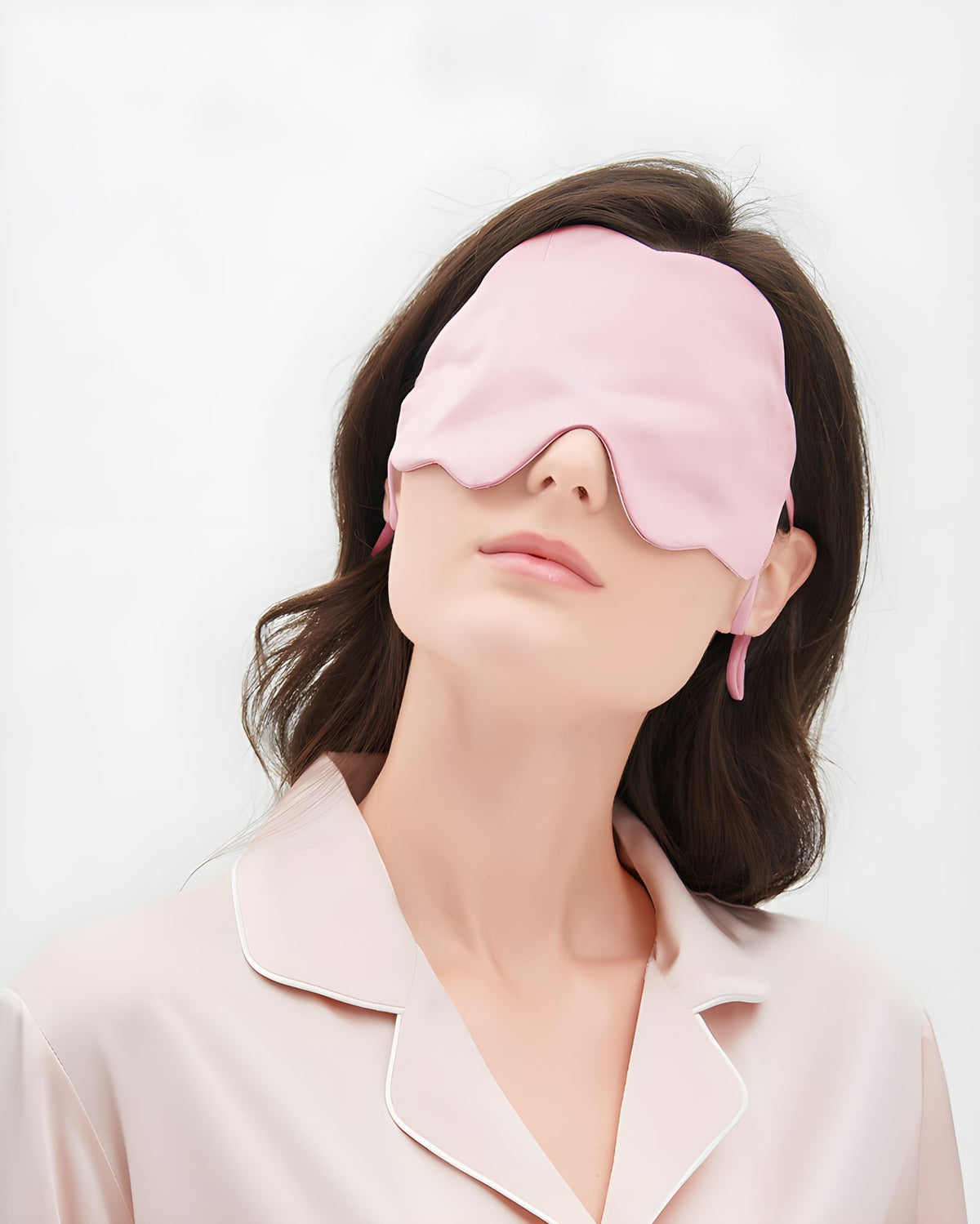 Darette Lights Out Silk Eye Mask in Blush worn by a model in silk pajamas, front view