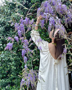 Back view of the Darette Rose to the Occasion Gown outdoors beneath a flowering wisteria vine